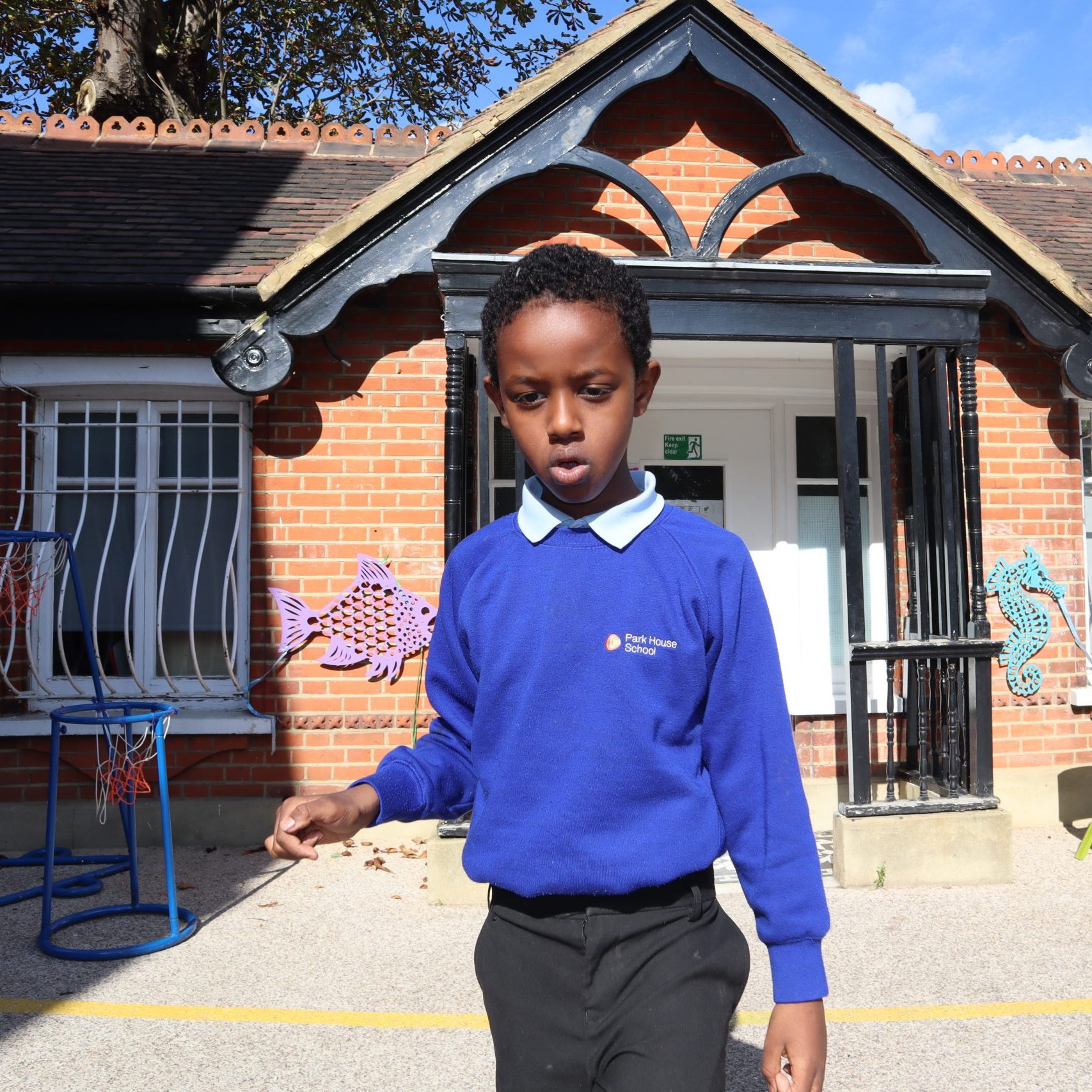 Boy wearing blue jumper stood in playground